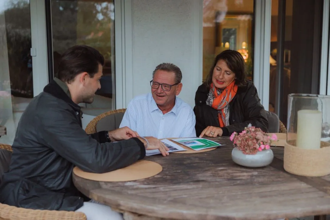 Henry Meyer berät ein Ehepaar am Tisch auf der Terrasse